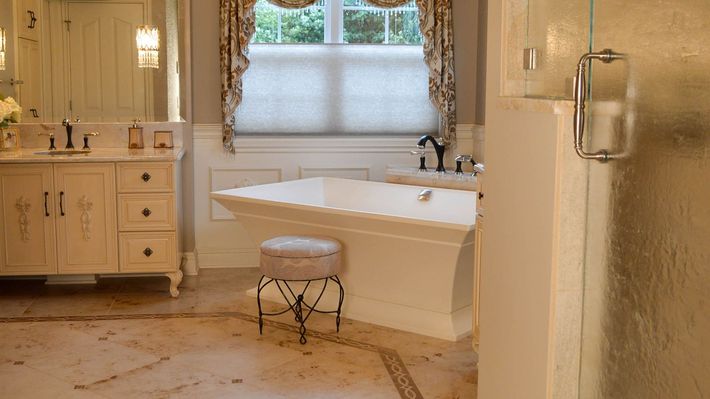 A bathroom with a tub, sink, mirror, and stool.