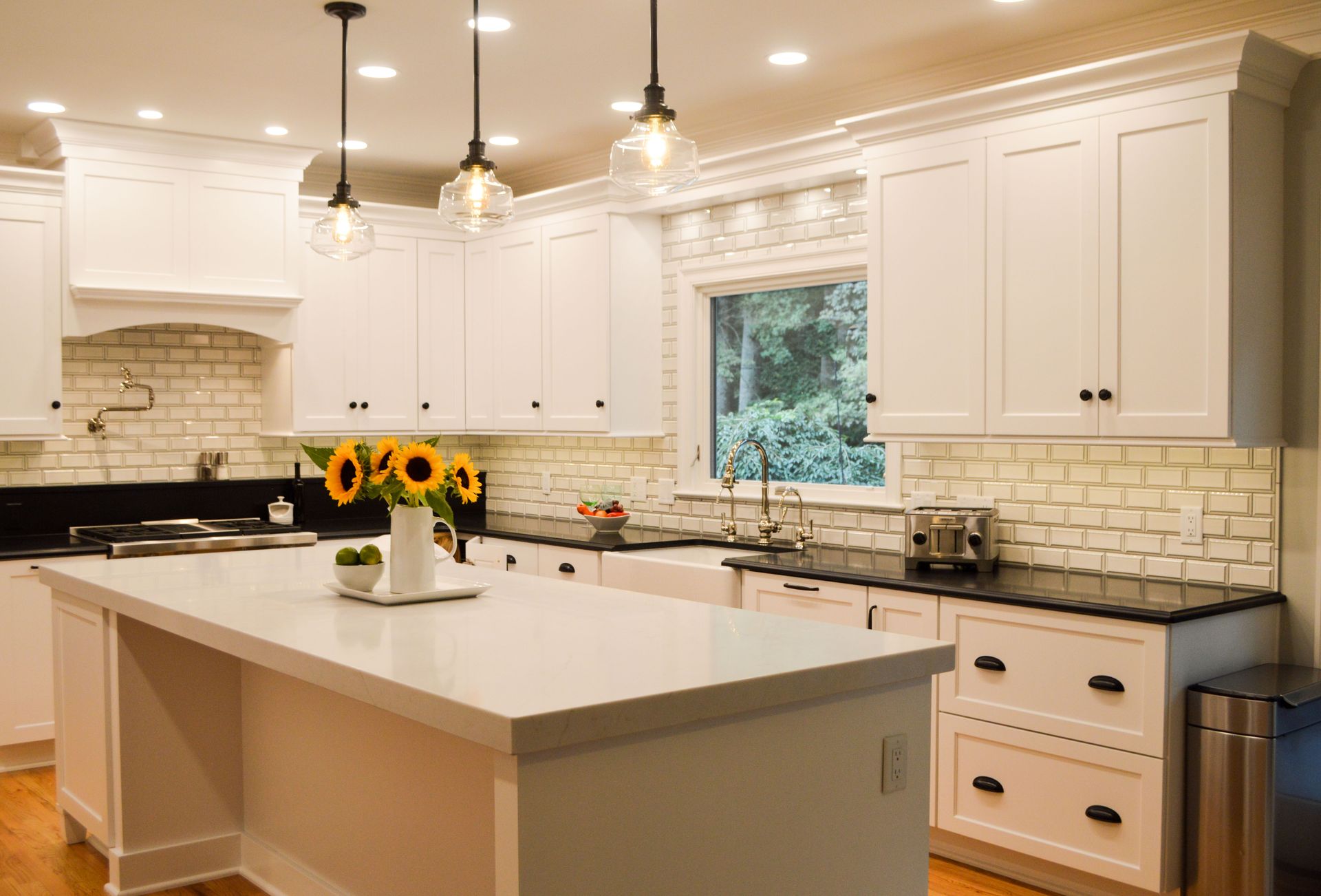 A kitchen with white cabinets , black counter tops , and a large island.