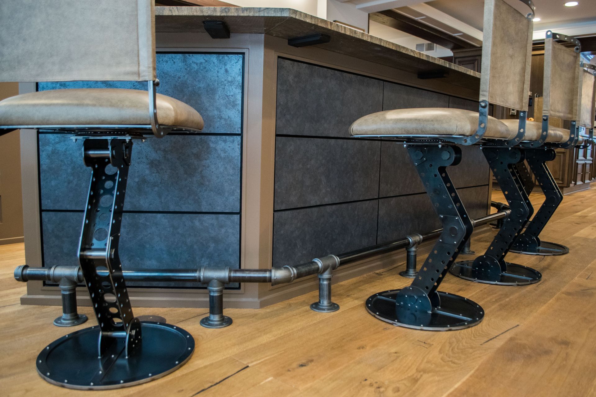 A row of bar stools are sitting next to each other on a wooden floor.