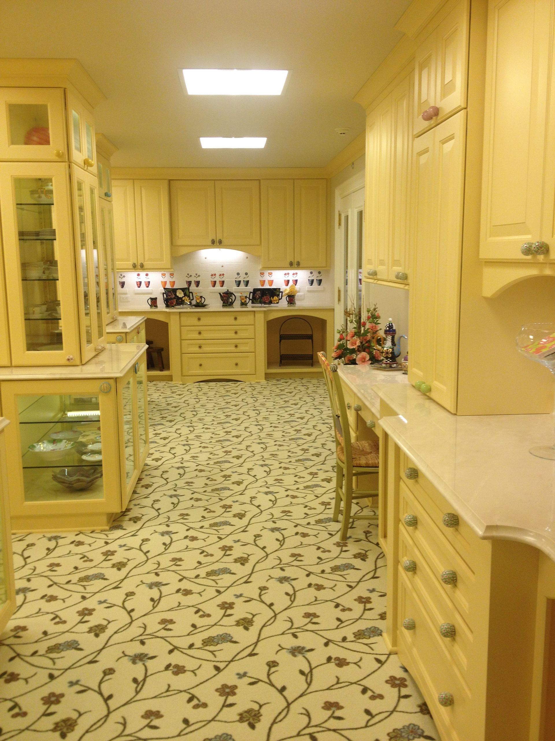 A kitchen with yellow cabinets and white counter tops
