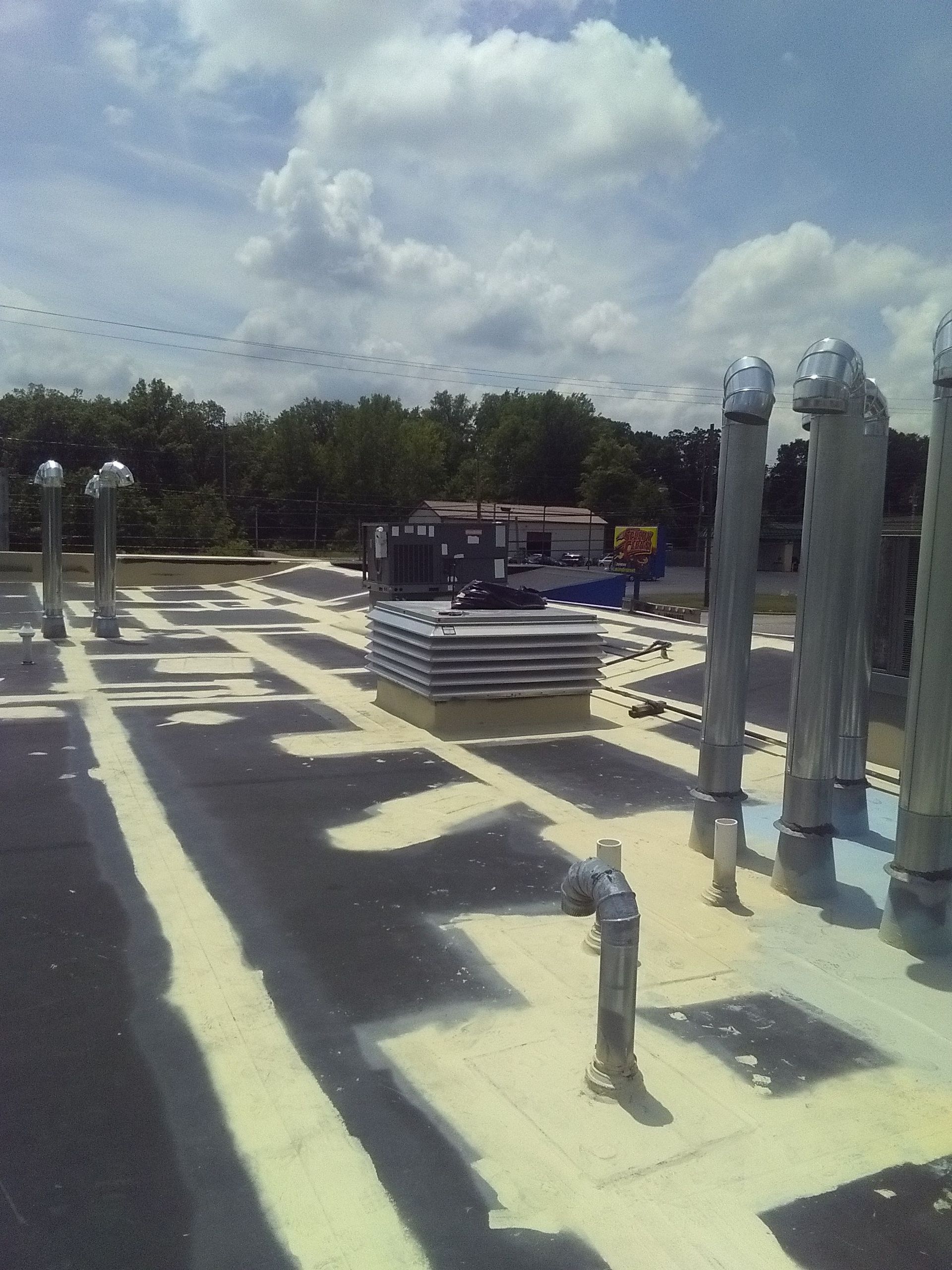 Rooftop with ventilation pipes and materials on a bright, sunny day.