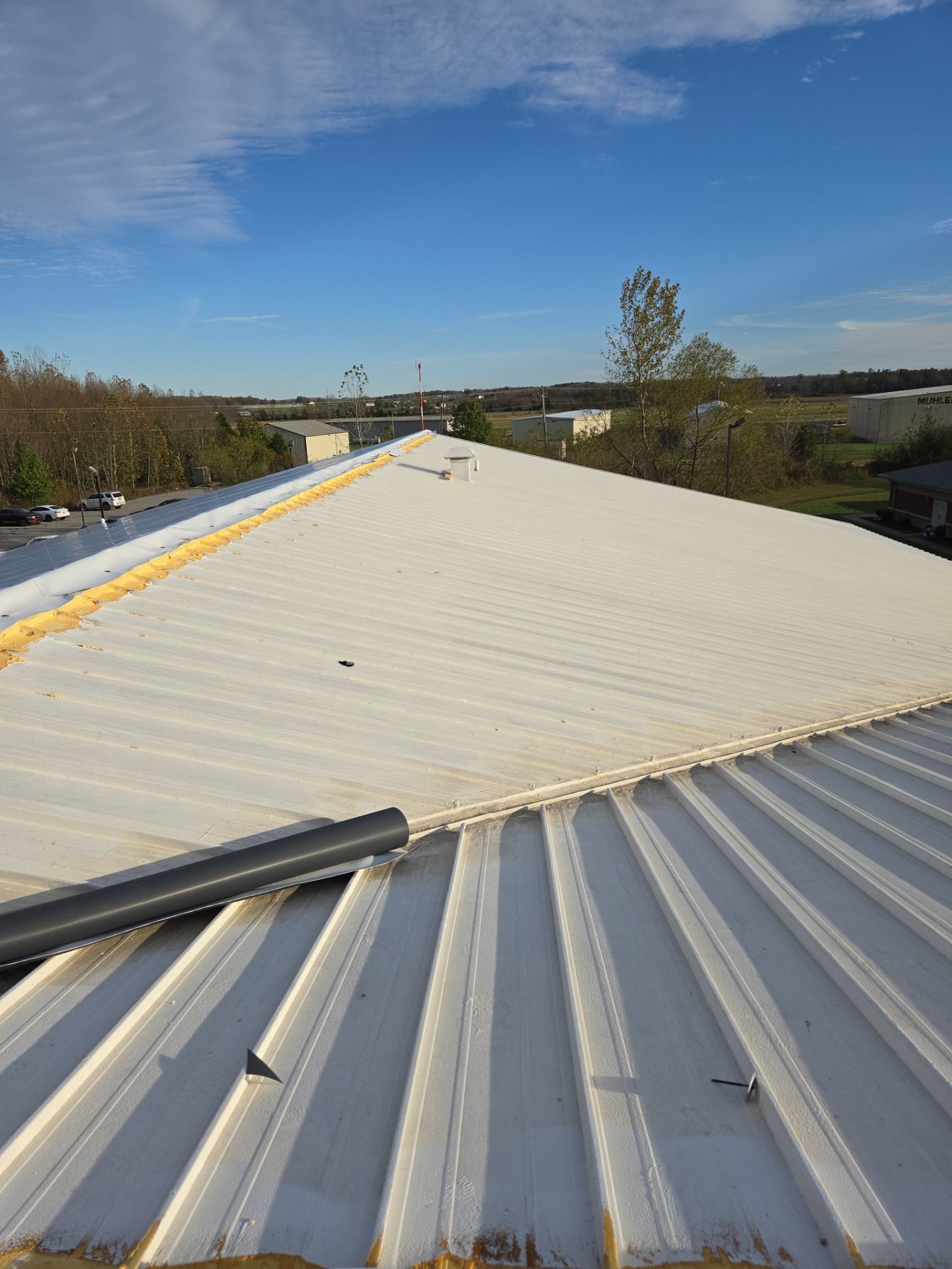 White metal roof with a gutter and blue sky.