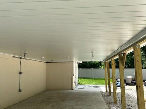 A carport with a white ceiling and wooden posts.