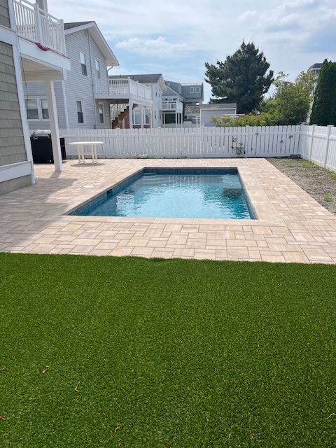 A large swimming pool in the backyard of a house with under deck