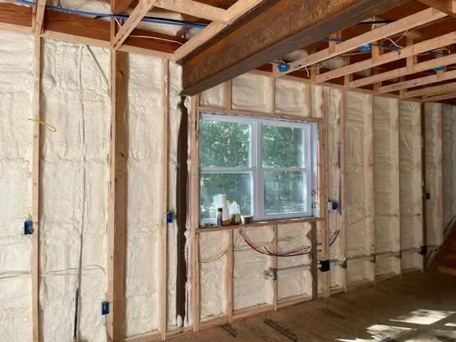 Interior of a building under construction, walls and ceiling with spray foam insulation. Window in the center.