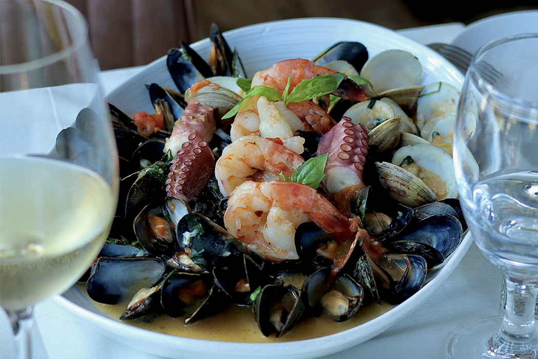 A plate of seafood is on a table next to a glass of wine