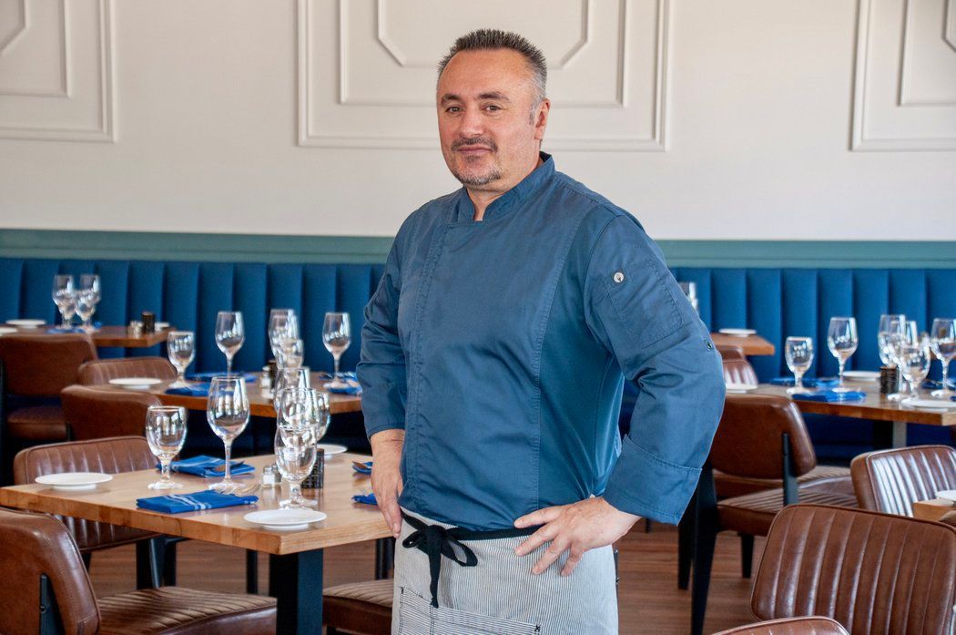 A man is standing in a restaurant with his hands on his hips.