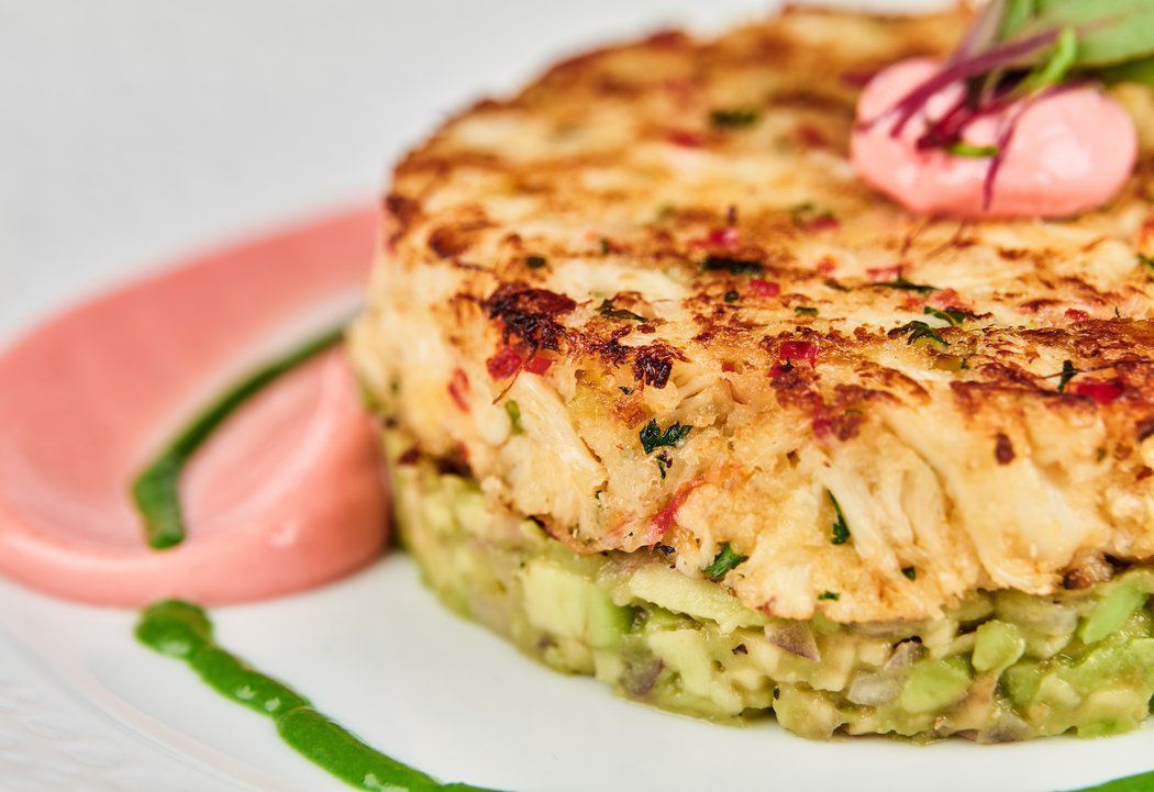 A close up of a crab cake on a plate with sauce.