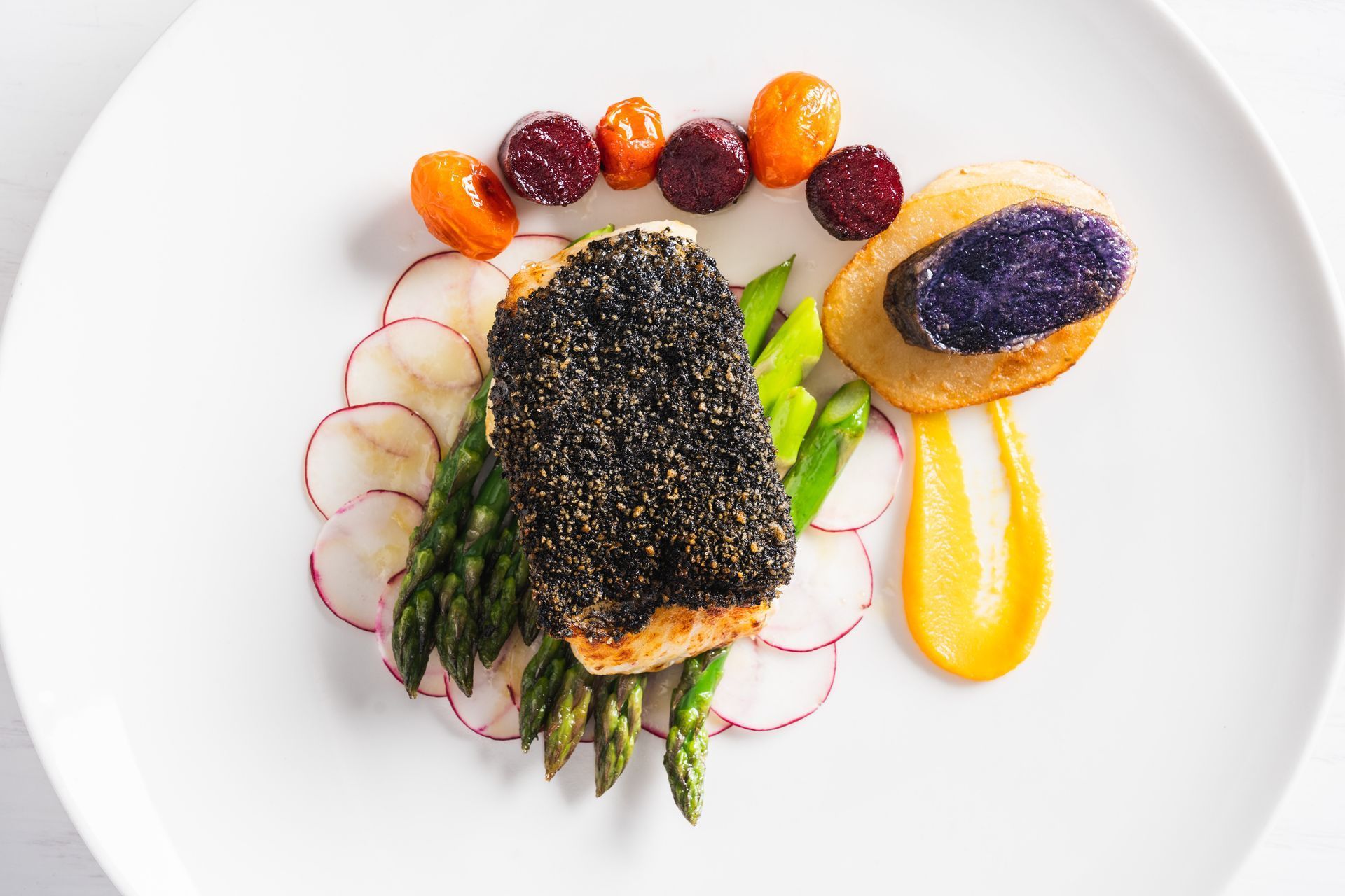 Plate of food: fish with black sesame crust, asparagus, radishes, potatoes, sauce, and tomatoes