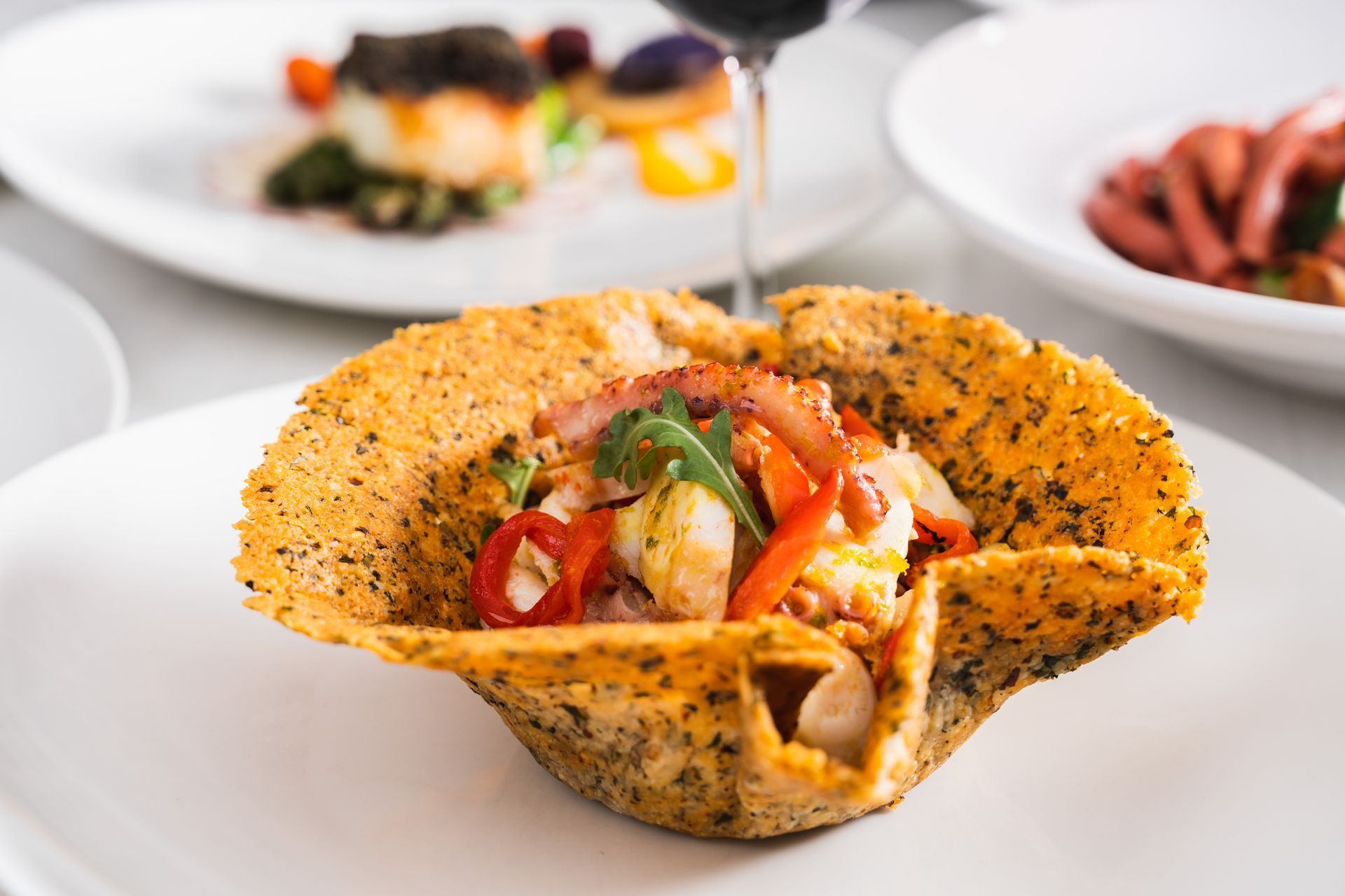 Octopus salad served in a crispy, edible bowl, on a white plate