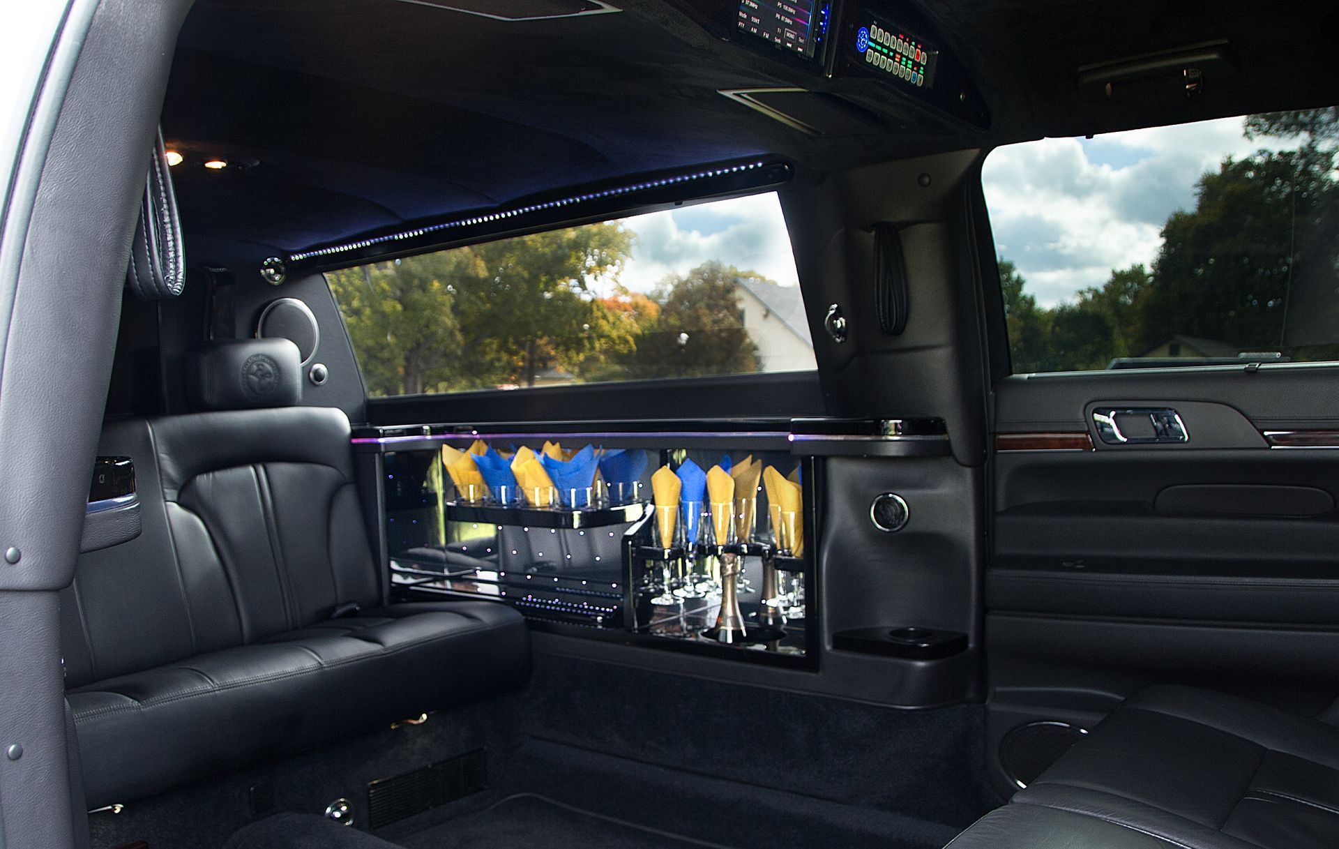 Luxury limousine interior with black leather seats and champagne glasses on a bar shelf