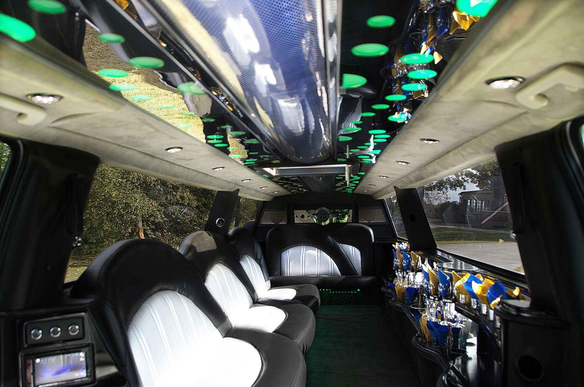 Interior of a party limo with white leather seats, neon ceiling lights, and tinted windows