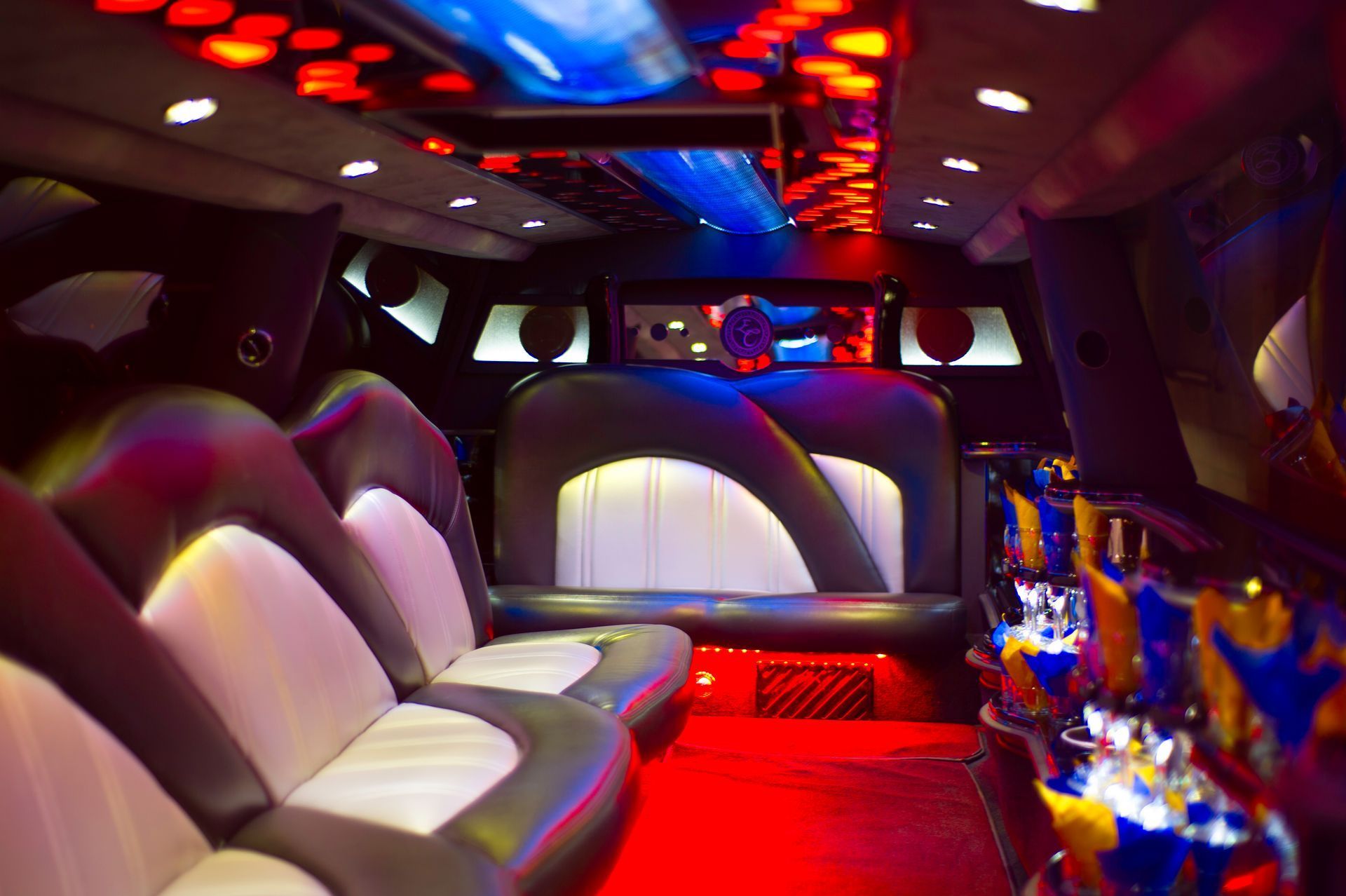 Luxury limo interior with red carpet, white leather seats, and colorful ceiling lights