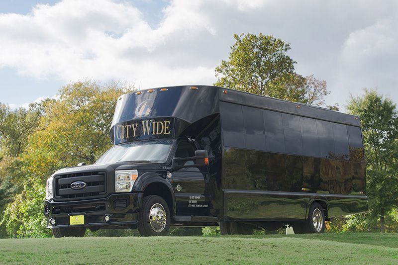 Black box truck parked on grass with “CITY WIDE” on the windshield under a cloudy sky
