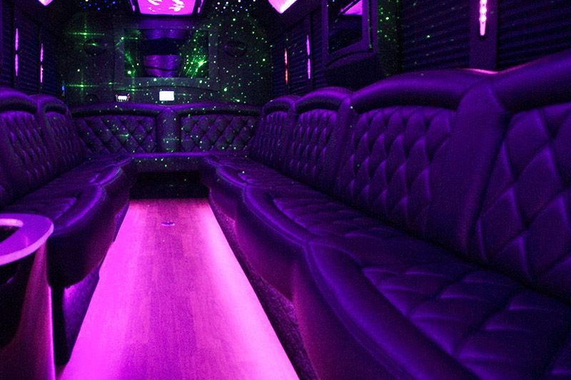 Purple-lit luxury limousine interior with tufted seats and a glowing aisle