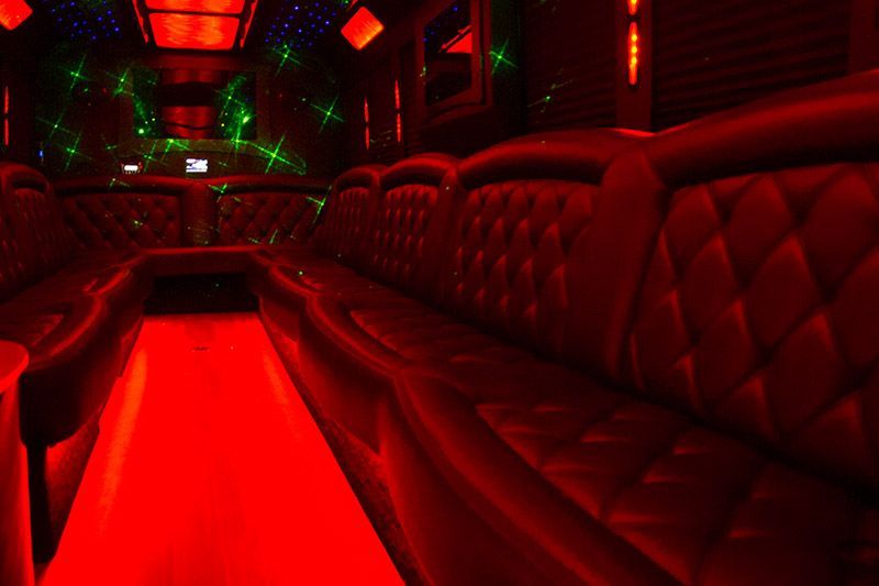 Red-lit luxury limousine interior with tufted leather seats and glowing floor lighting