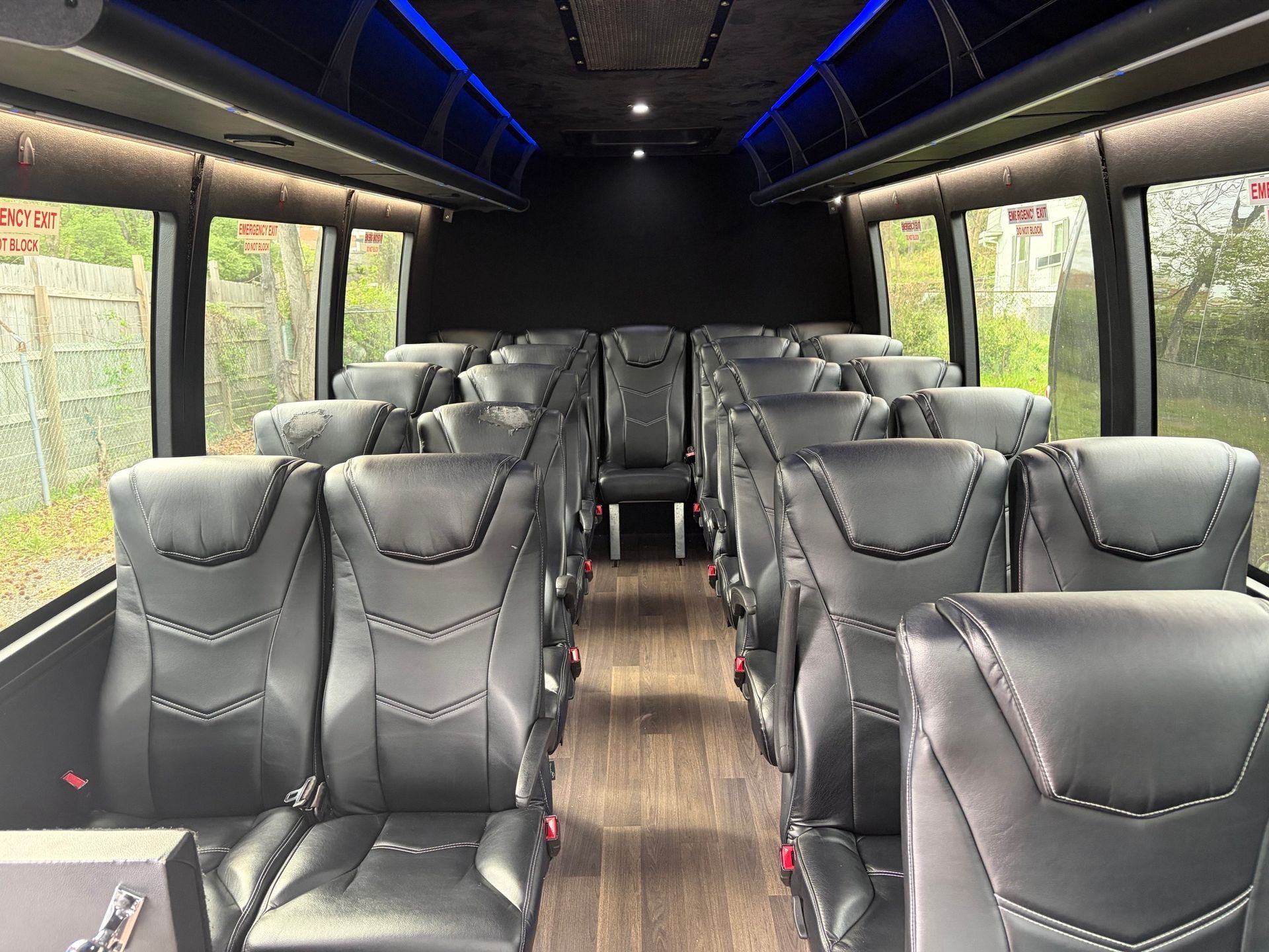 Empty modern bus interior with rows of black seats and wood-look flooring