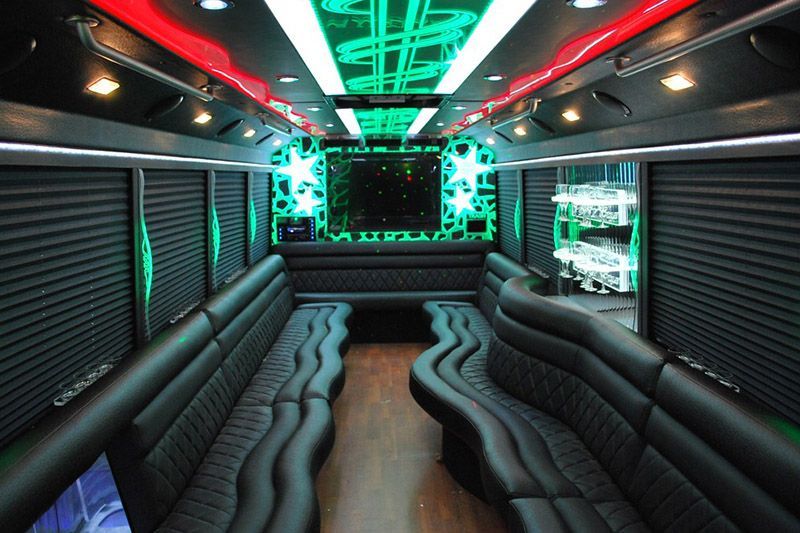 Empty luxury bus interior with neon green and red ceiling lights and black leather seating