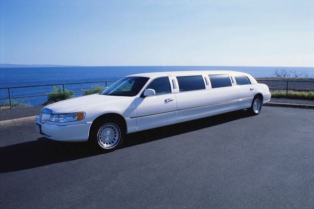 White stretch limousine parked by the ocean on a sunny day