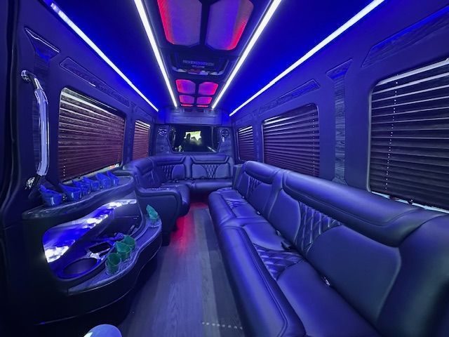 Neon-lit luxury bus lounge with black leather seats and blue-purple LED lighting