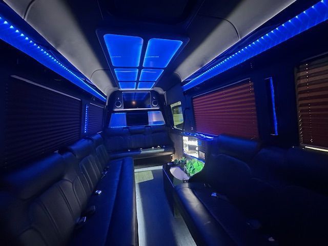 Luxury limo interior with blue LED ceiling lights and black leather seats, viewed from the back