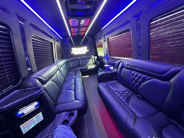 Purple-lit luxury van interior with black leather bench seats and a screen at the front