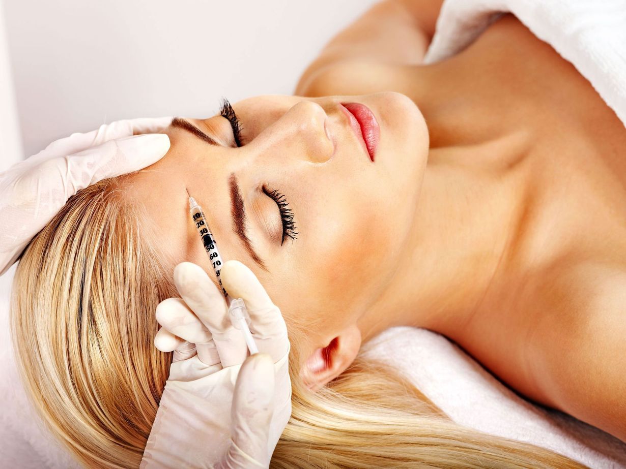 Woman receiving a facial treatment while lying on a spa table, eyes closed and head wrapped in a towel