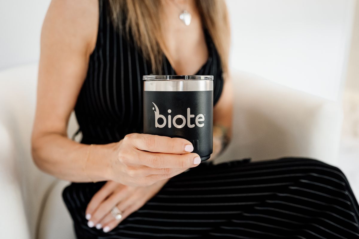 Hand holding a black Biote candle against a black-and-white striped outfit