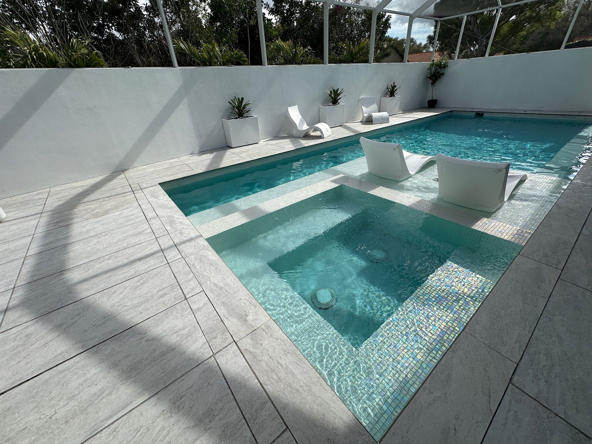 Modern backyard pool with turquoise water, white tile deck, and built-in square lounge seating