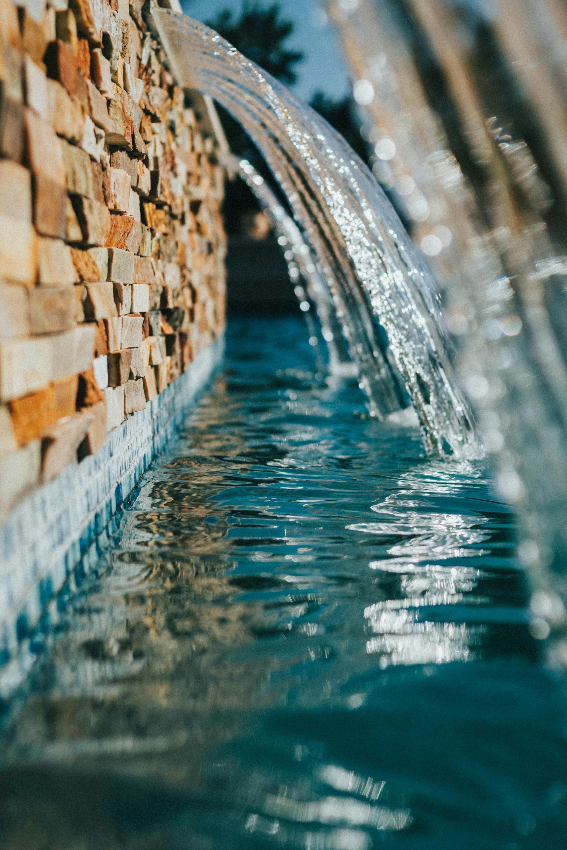 Close-up of water flowing from tiled fountain spouts into a blue pool