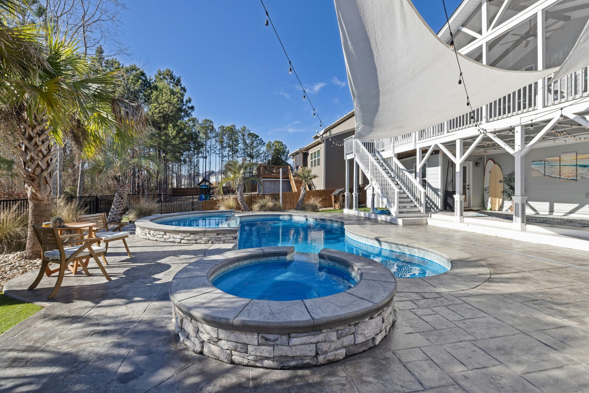 Courtyard with a small blue pool, stone patio, chairs, and a white spiral staircase.