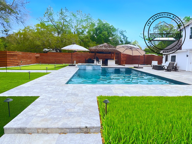 Backyard pool with stone walkway, green lawn, wooden fence, and white patio umbrellas on a sunny day