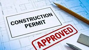 Construction permit document stamped 'APPROVED' with pencil and ruler on a blueprint background