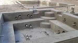Concrete structure with stepped platforms and circular openings, resembling a construction or foundation pit