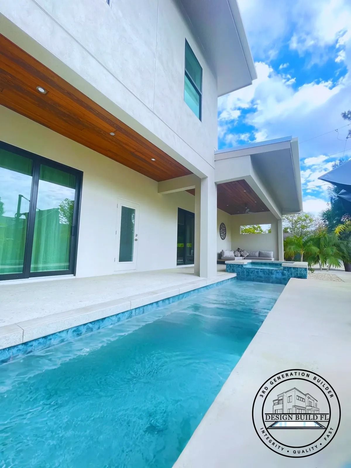 Modern white villa with a long turquoise lap pool and covered patio under a blue sky