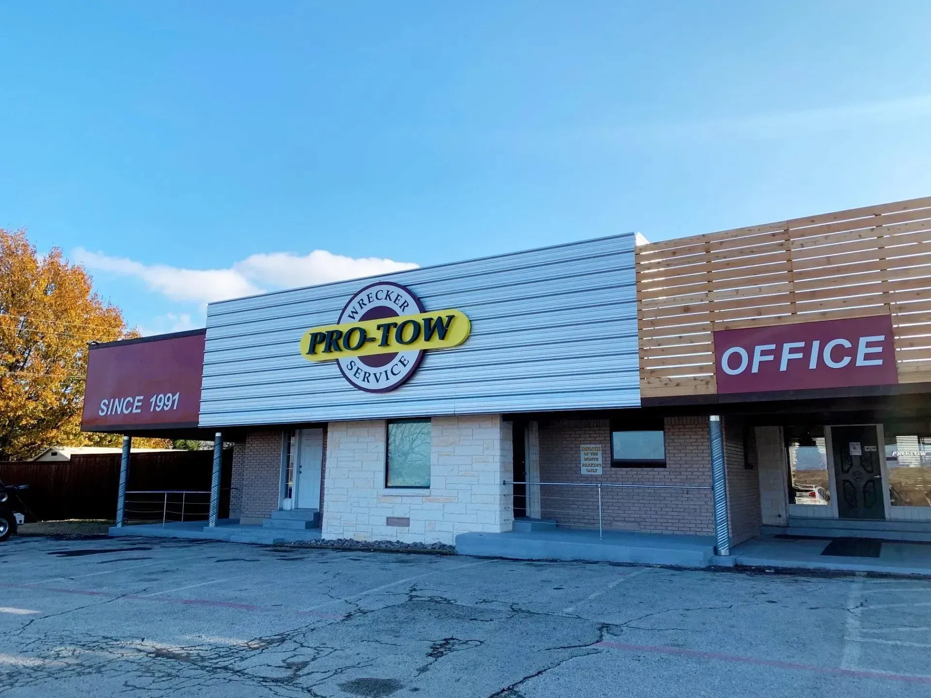 the front of a pro-tow company building with a parking lot in front of it .