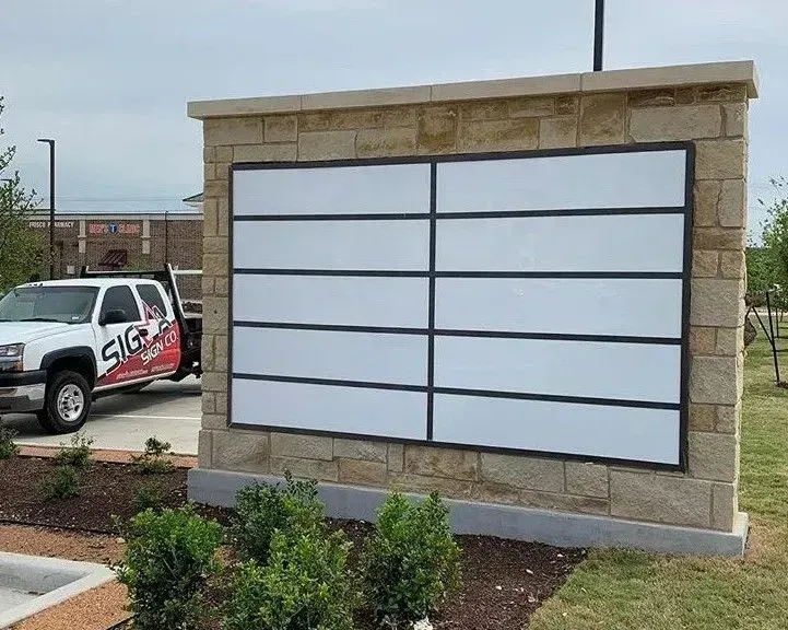 a white truck is parked in front of a brick wall with a sign on it .