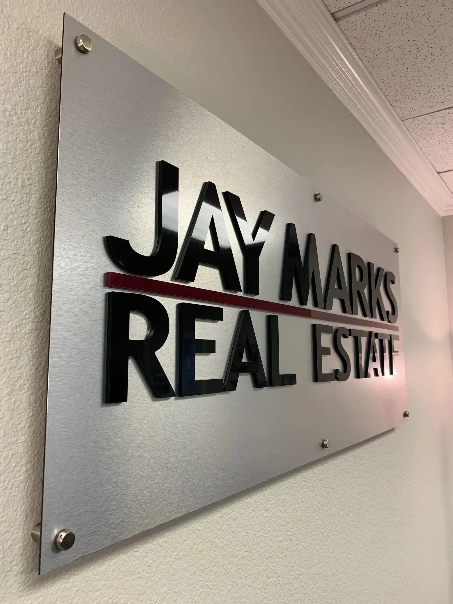 Dimensional acrylic letters on brushed aluminum backer installed on office wall with standoffs.