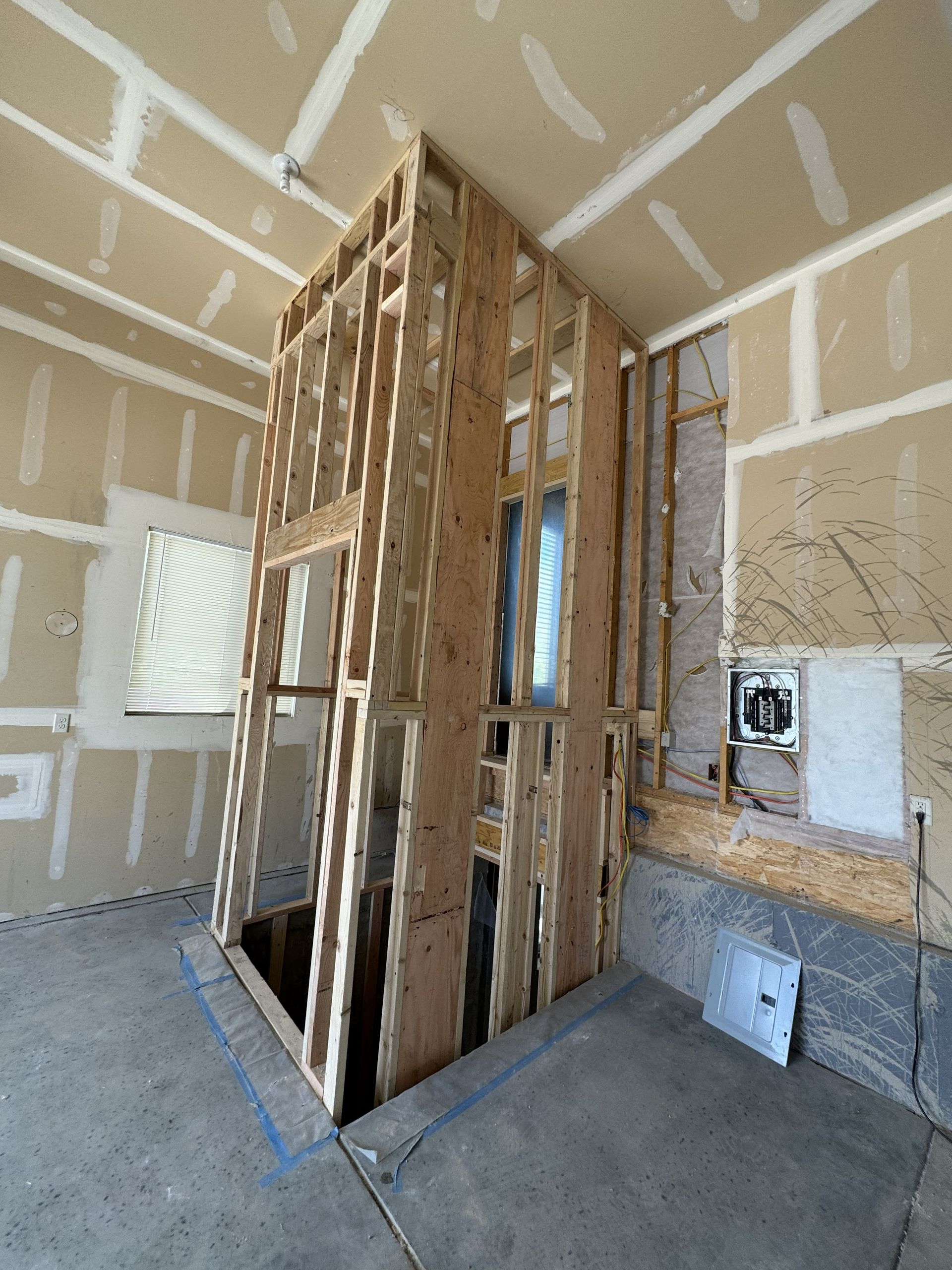 Interior view of framed wall construction, doorway, and window, unfinished construction site.