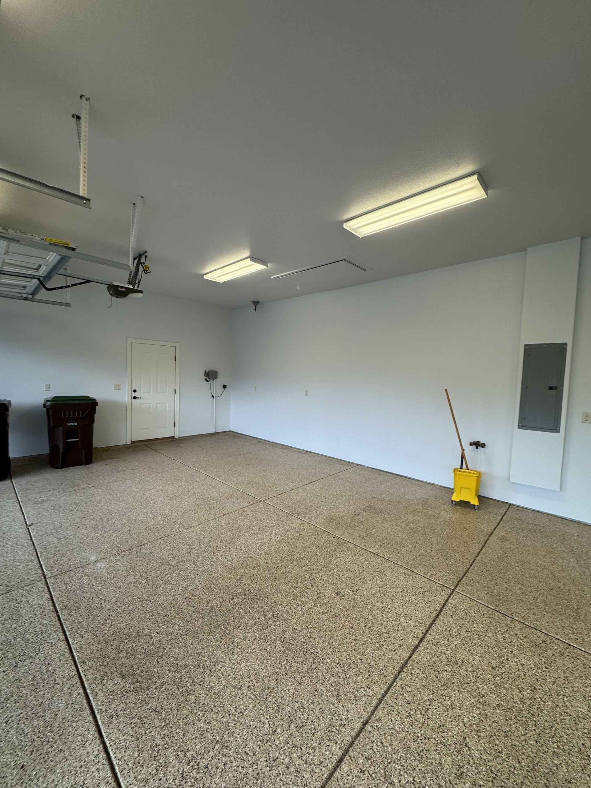 Empty garage with speckled floor, white walls, and a closed door.