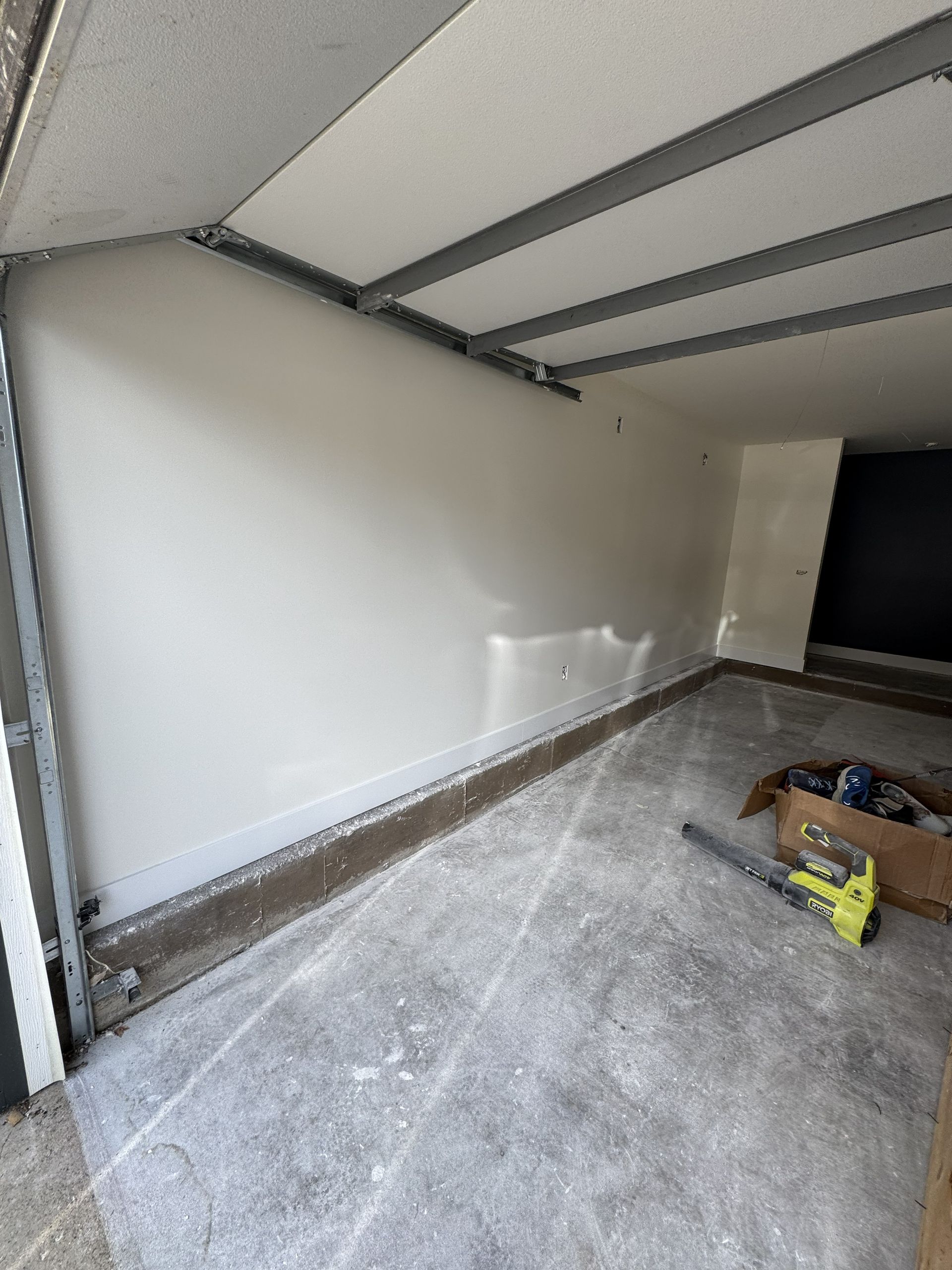 Interior of a room under construction, with white walls and unfinished concrete floor.