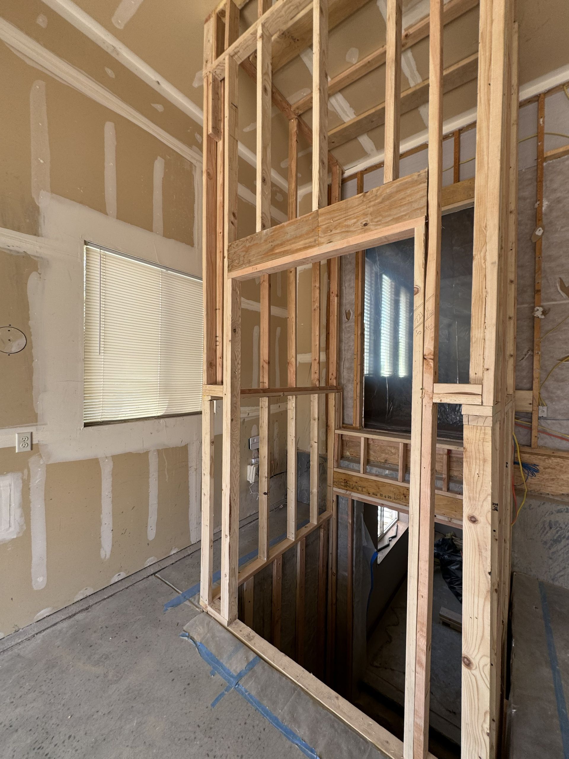 Wooden elevator shaft under construction; drywall and concrete surfaces; light wood framing.