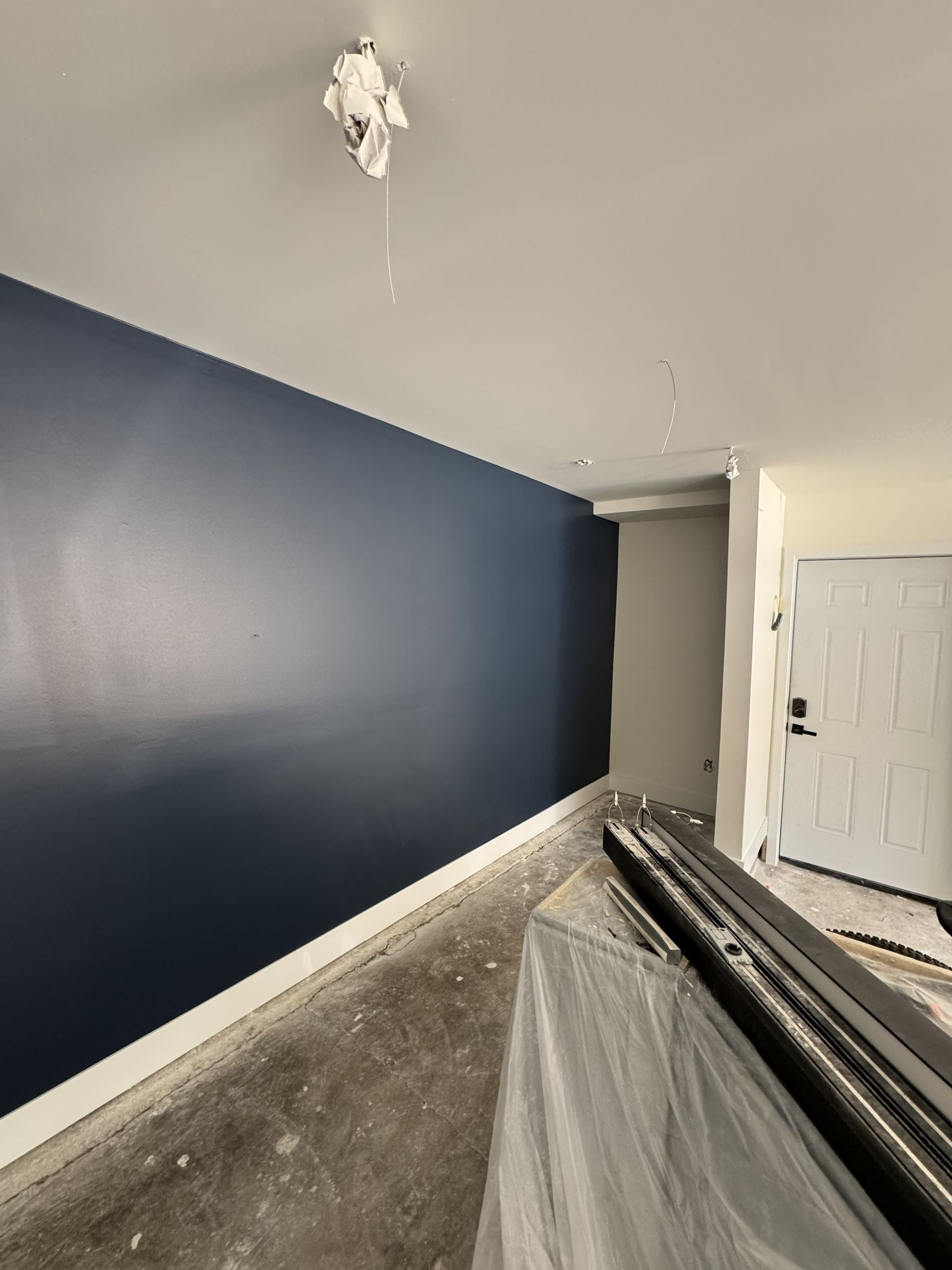 Interior room with blue accent wall, white trim, and a white door.