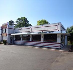 A diner with a lot of windows is sitting on the side of the road.