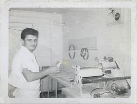 A man is standing in front of a machine in a kitchen.