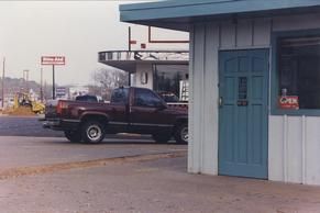 A truck is parked in front of a building with a blue door.