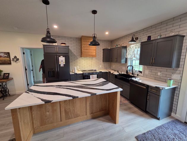Modern kitchen with dark cabinets, white brick backsplash, island, and striped rug