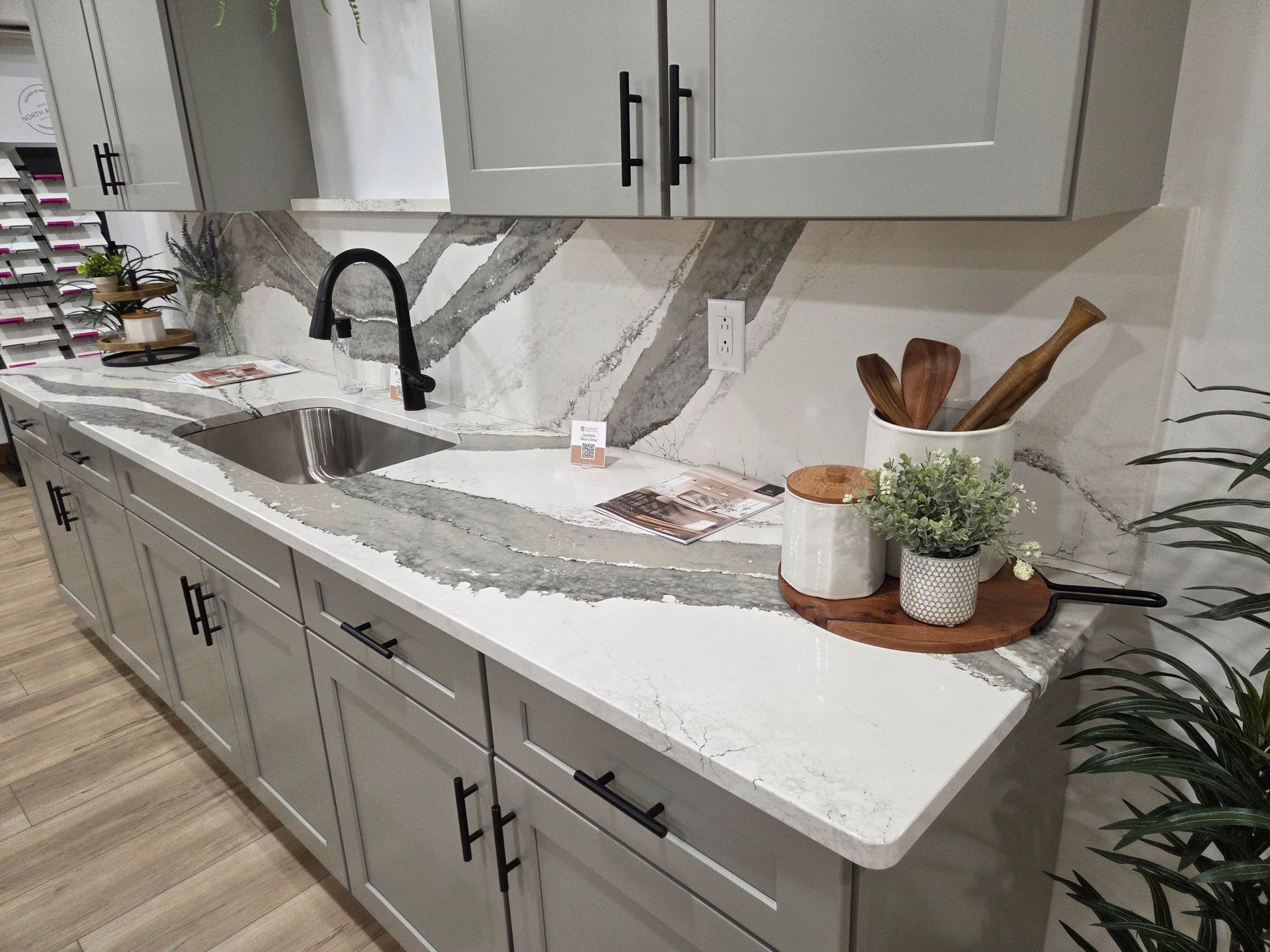 Modern kitchen with white countertops, gray cabinets, farmhouse sink, and decorative items on the island