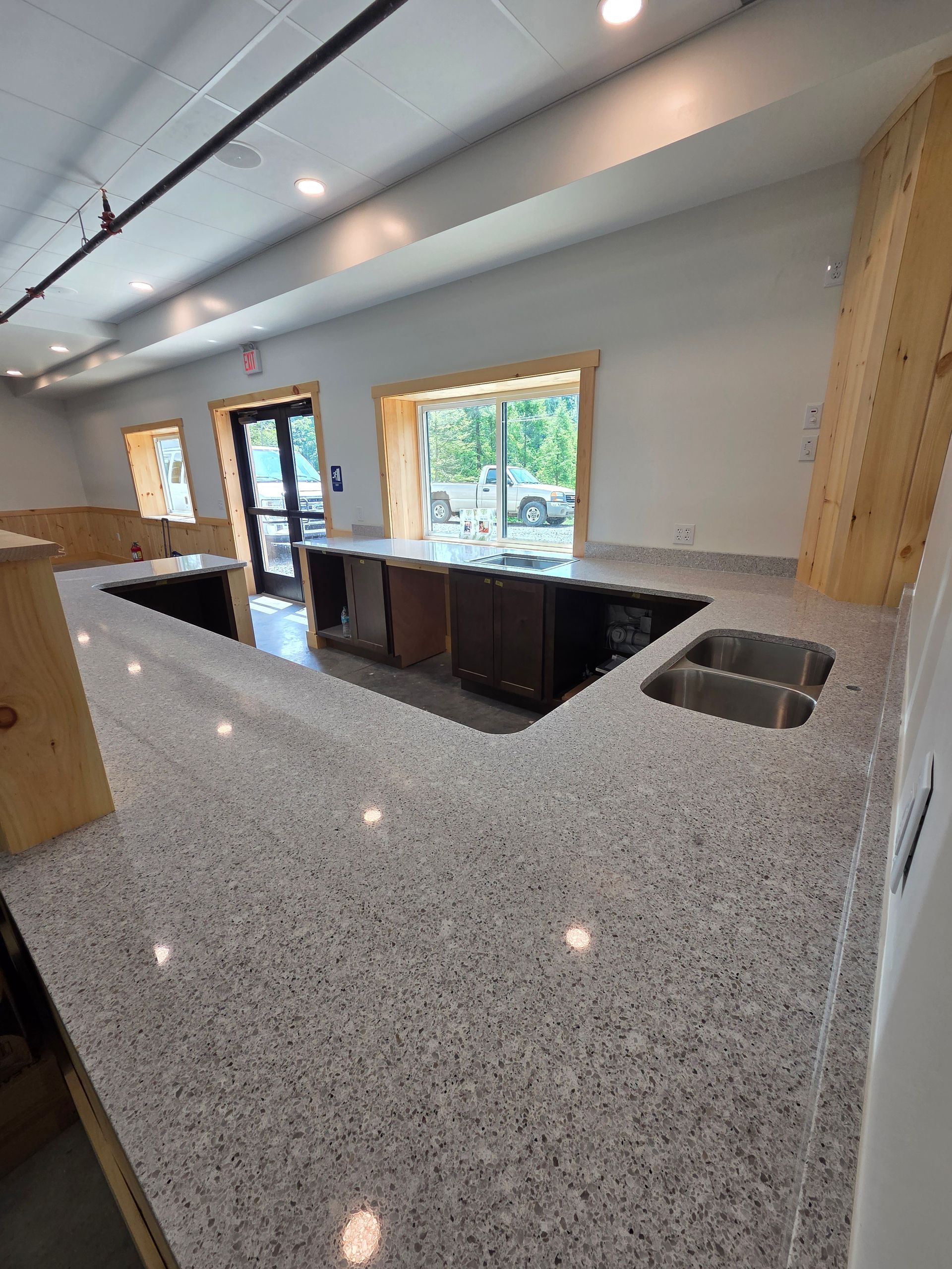 Modern kitchen with speckled granite island, black cabinets, large windows, and recessed lighting
