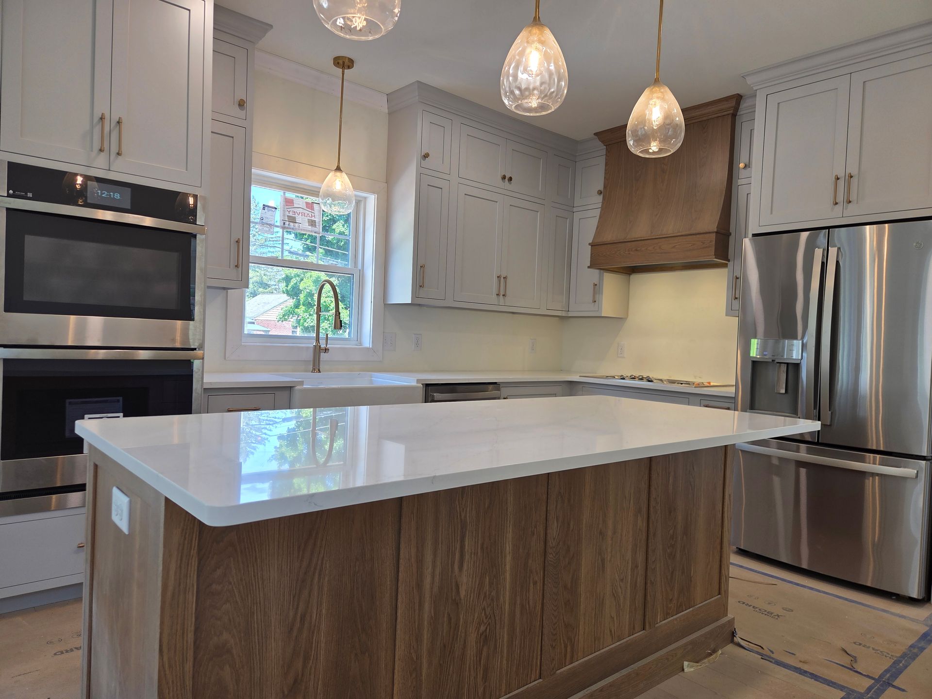 Modern kitchen with white cabinets, stainless appliances, pendant lights, and a large island with wood paneling